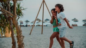 Two children enjoy a playful walk on a sandy beach, capturing summer fun.